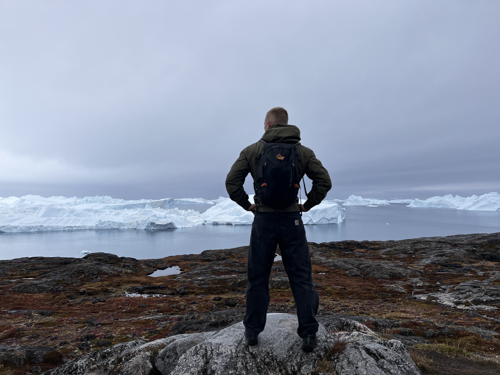 Andreas Skyt standing on a rock overlooking a field of icebergs in Greenland